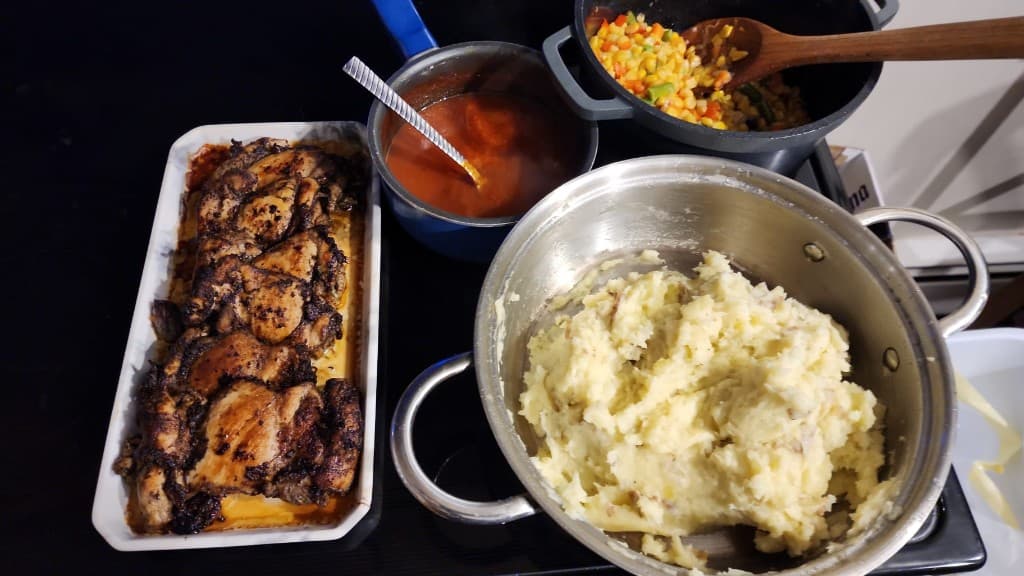 Jerk-style chicken, sides, and sauces — kitchen line for service
